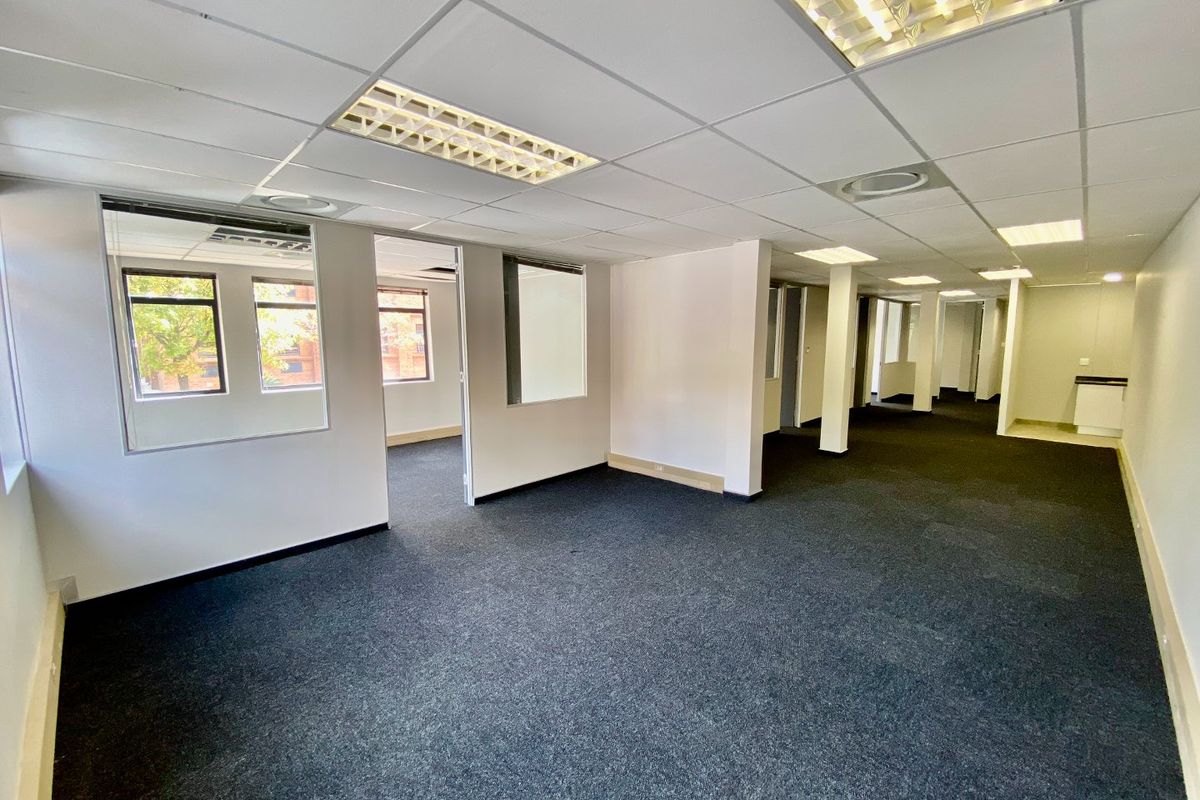 An open-plan commercial office space featuring suspended ceilings, recessed lighting, carpeted flooring, and internal glass partitions, offering a versatile layout for business operations.