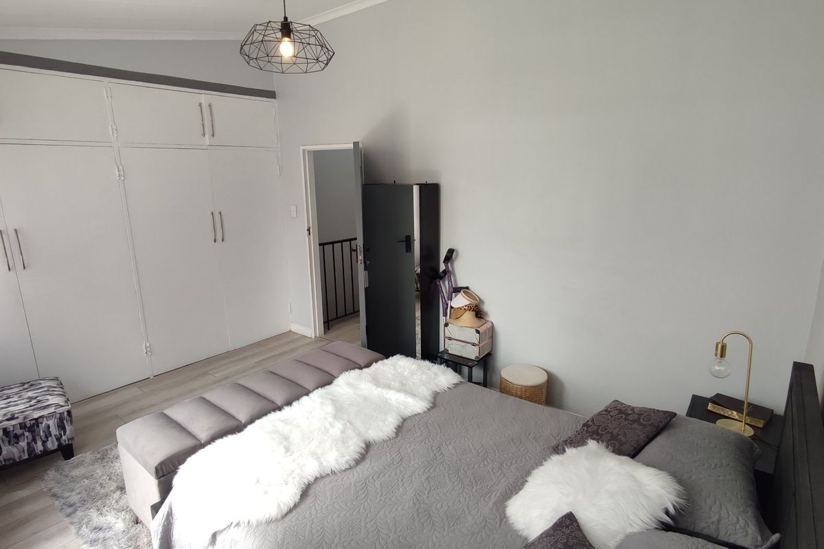 A well-maintained bedroom featuring neutral walls, laminate flooring, and extensive built-in cupboard storage.