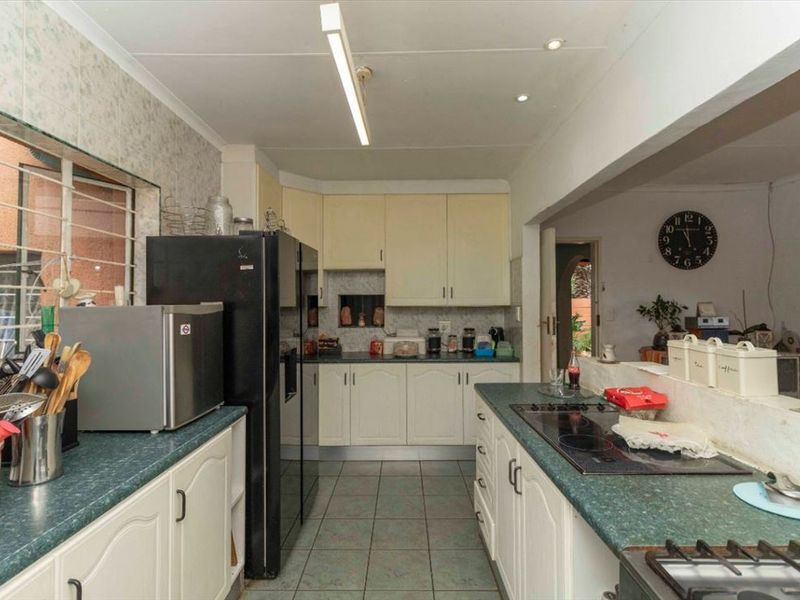 A functional kitchen featuring laminate countertops, built-in cabinetry, and tiled flooring, offering a practical layout with an integrated electric hob.