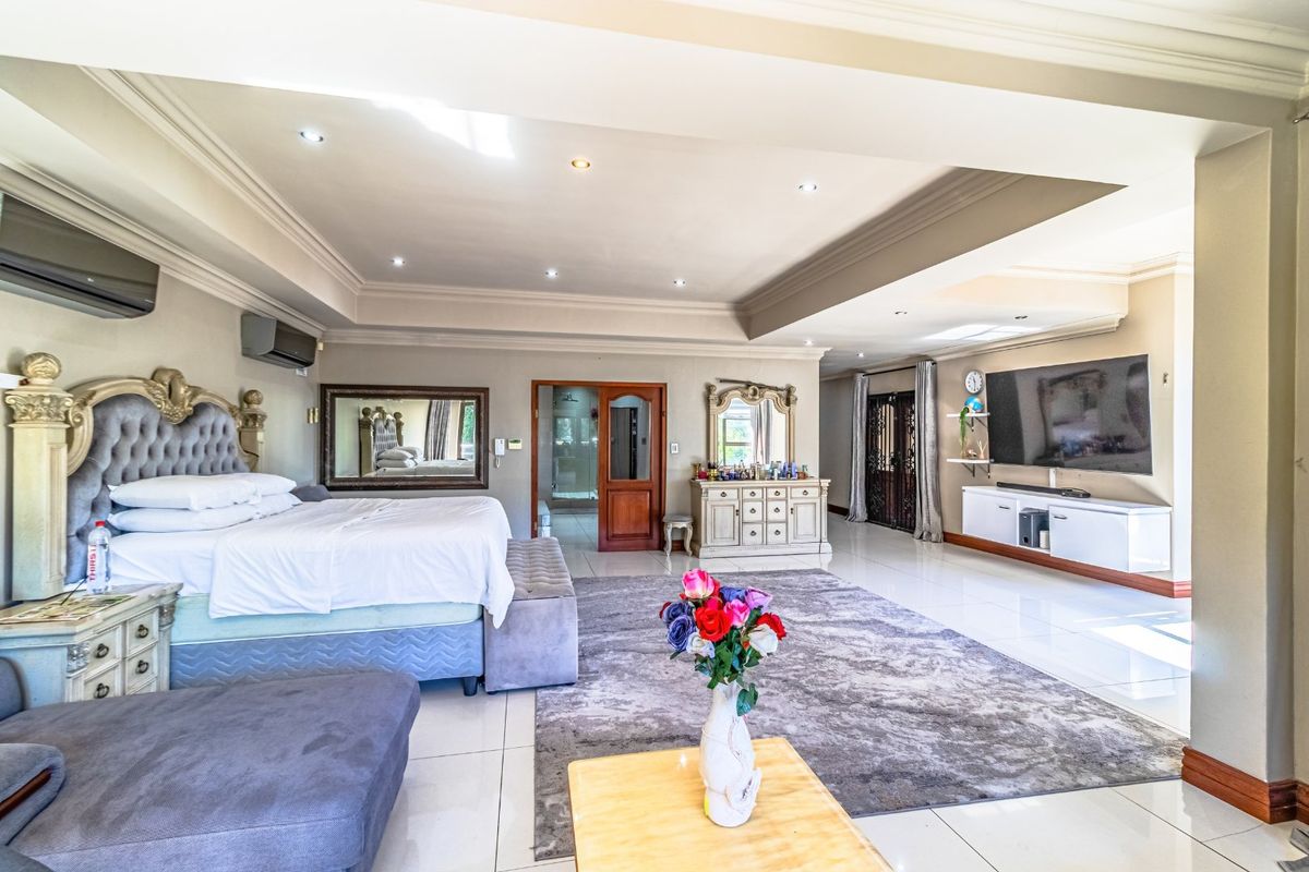 Spacious primary bedroom featuring recessed ceiling lighting, cove molding, tiled flooring, and a wall-mounted air conditioning unit.