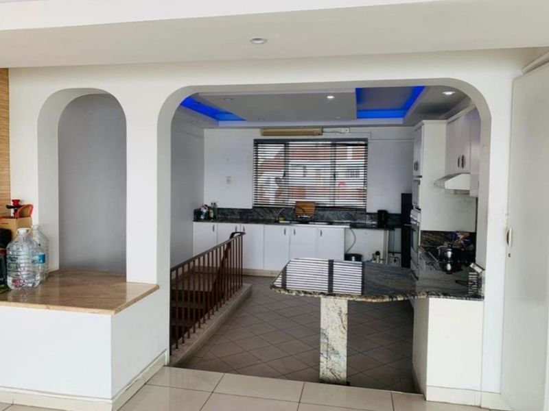 A functional kitchen featuring granite countertops, built-in cabinetry, and integrated appliances, with a unique arched opening overlooking a staircase.