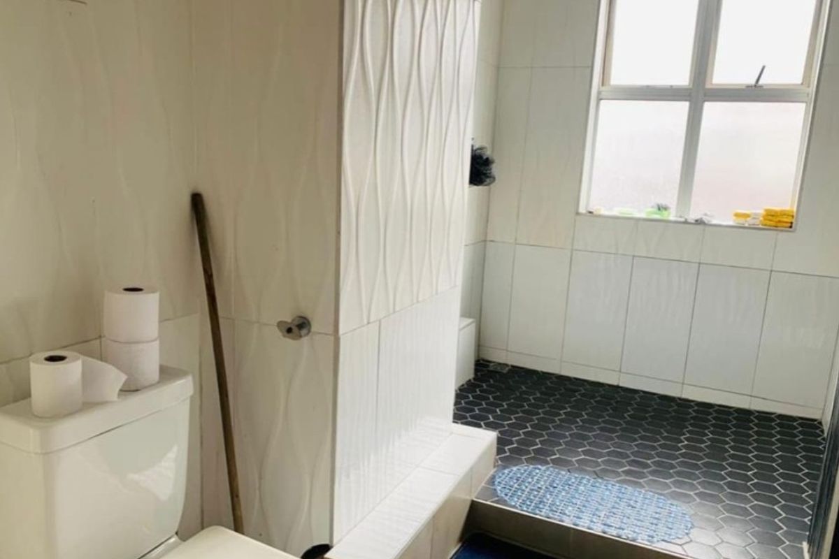 A modern bathroom featuring a walk-in shower with a rain shower head, textured wall tiles, and contrasting hexagonal floor tiles.