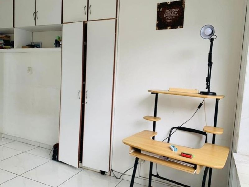 A bedroom featuring white built-in cupboards and tiled flooring, providing functional storage space within the apartment.