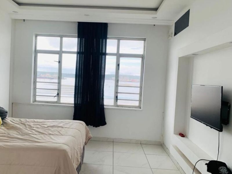A bright bedroom featuring tiled flooring, a built-in media niche, and large windows with views, offering a clean and modern living space.