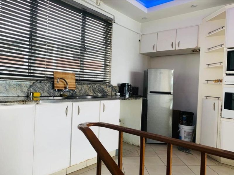 Functional kitchen featuring white cabinetry, granite countertops, built-in oven and microwave, tiled flooring, and large window with venetian blinds.