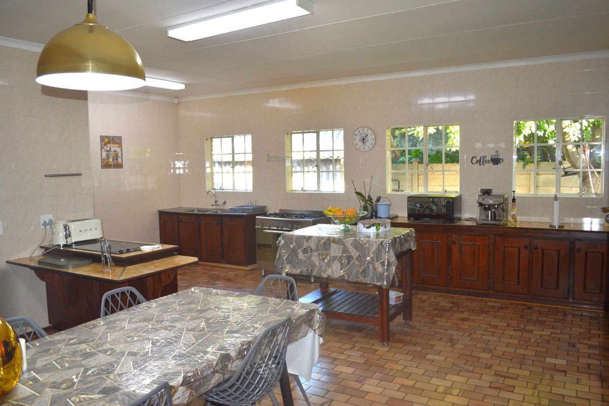 Spacious kitchen featuring extensive wooden cabinetry, gas stove, double sink, and durable brick-style floor tiles with ample natural light from multiple windows.