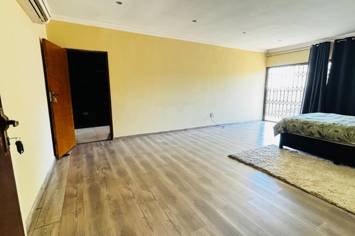Spacious bedroom featuring laminate flooring, recessed lighting, and a security gate leading to an outdoor area.