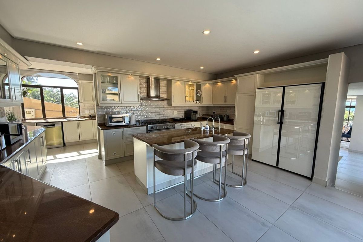 Modern kitchen featuring a central island with granite countertops, subway tile backsplash, stainless steel appliances, and ample cabinetry with recessed lighting.