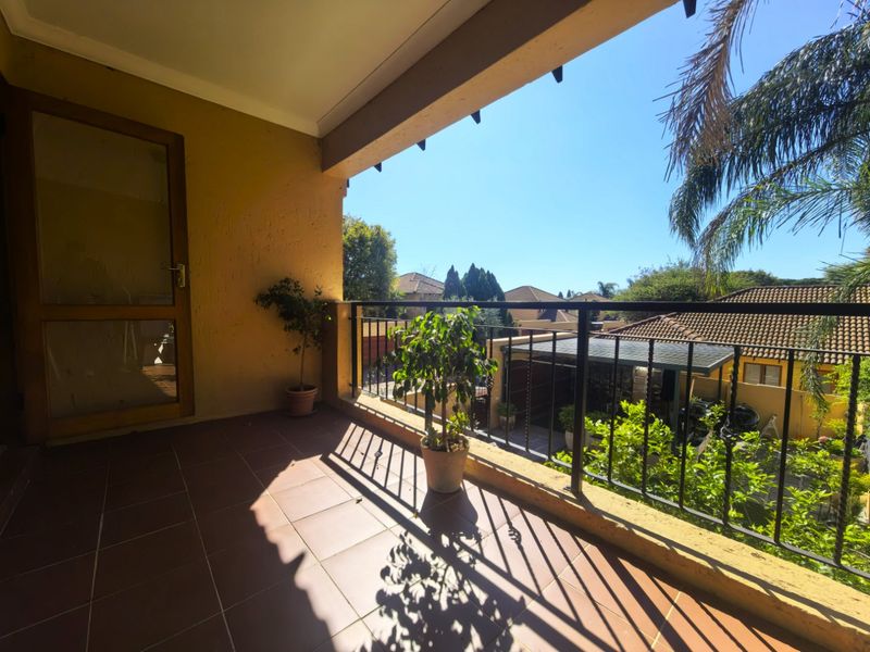 A covered balcony featuring tiled flooring and a metal balustrade, offering an elevated view of the surrounding residential area.