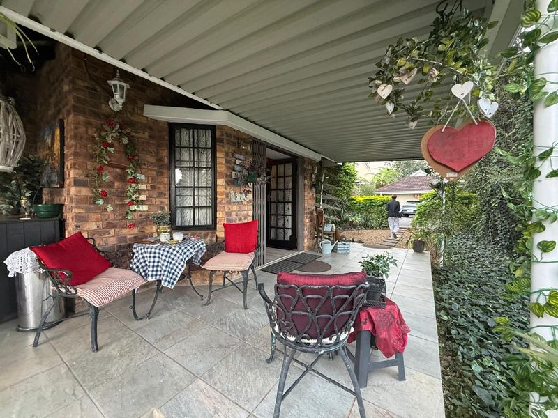 A covered patio area featuring exposed brick walls, tiled flooring, and direct access to the home entrance.