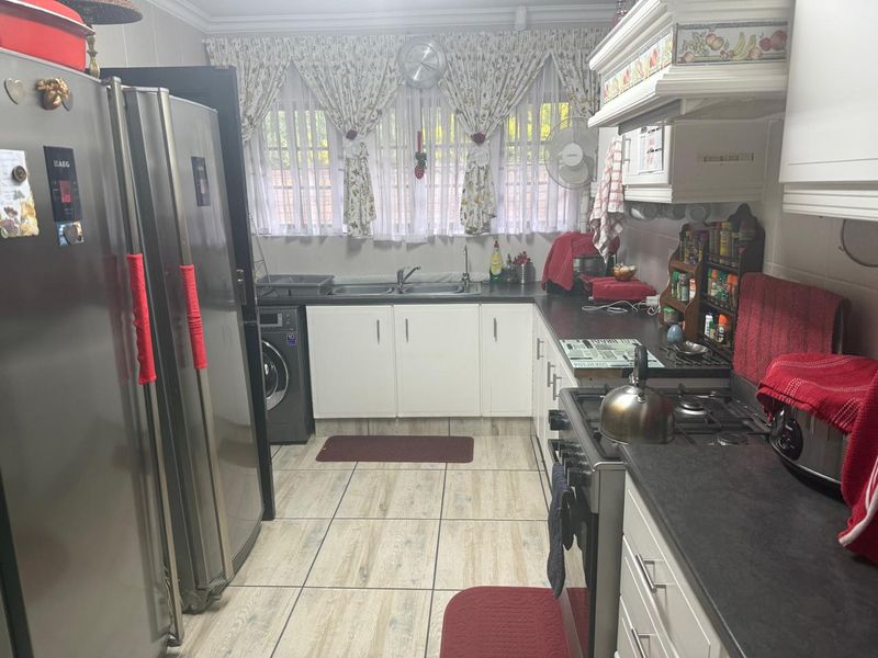 A functional kitchen featuring white cabinetry, dark countertops, a gas stove, and integrated laundry plumbing.