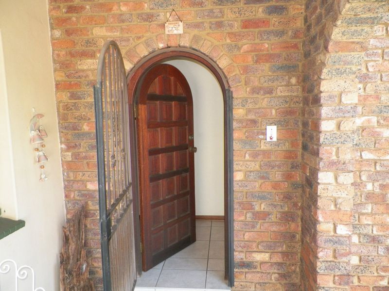 Entrance area featuring a rustic exposed brick facade with an arched timber door and security gate.