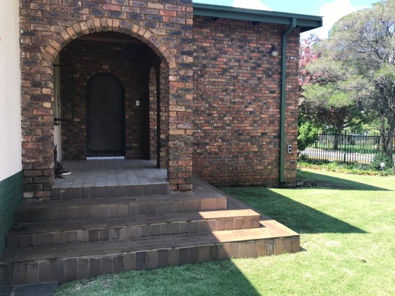 A front entrance featuring a classic brick facade, arched porch entryway, and tiled steps leading to a secure front door.