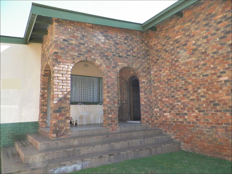Front entrance of a house featuring a brick facade with an arched porch and tiled steps.