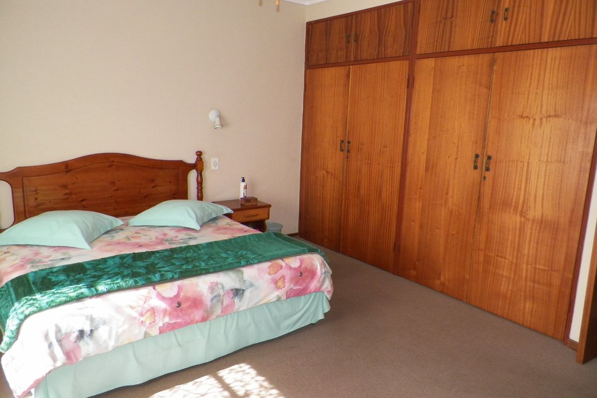 A bedroom featuring wall-to-wall built-in wooden cupboards and neutral carpeting, offering a functional space with classic storage solutions.
