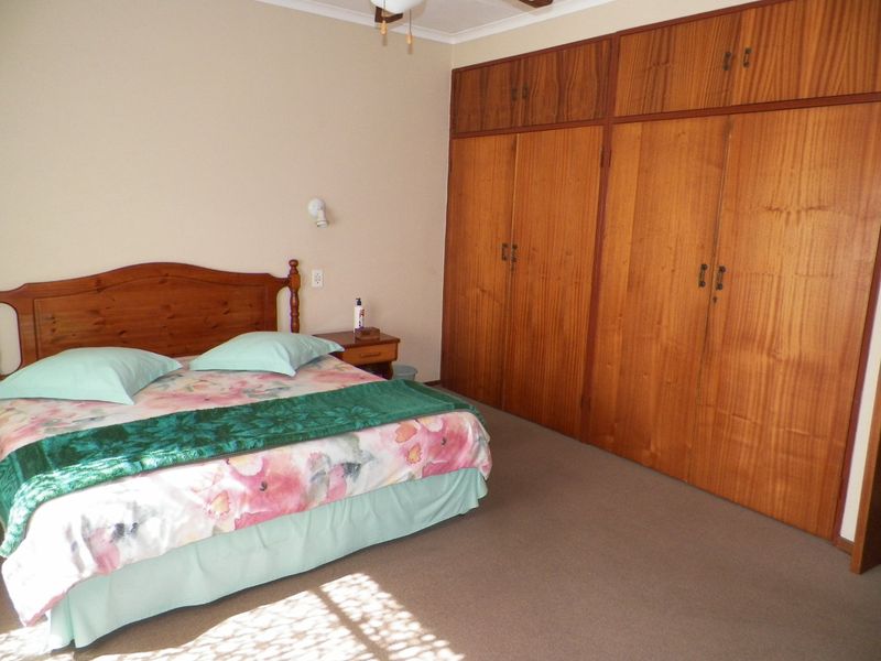 A bedroom featuring wall-to-wall built-in wooden cupboards and neutral carpeting, offering a functional space with classic storage solutions.
