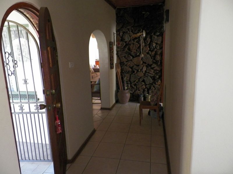 Entrance hallway featuring tiled flooring, an arched doorway, and a rustic stone feature wall, leading into the main living area.