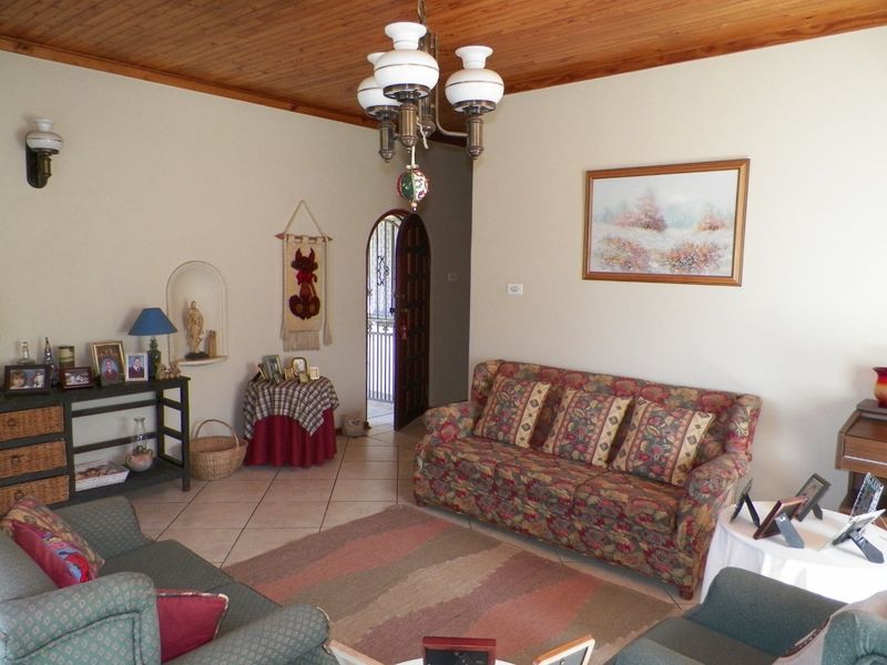 A living room featuring a timber-clad ceiling, ceramic floor tiles, and a decorative wall niche, leading to an arched entrance.