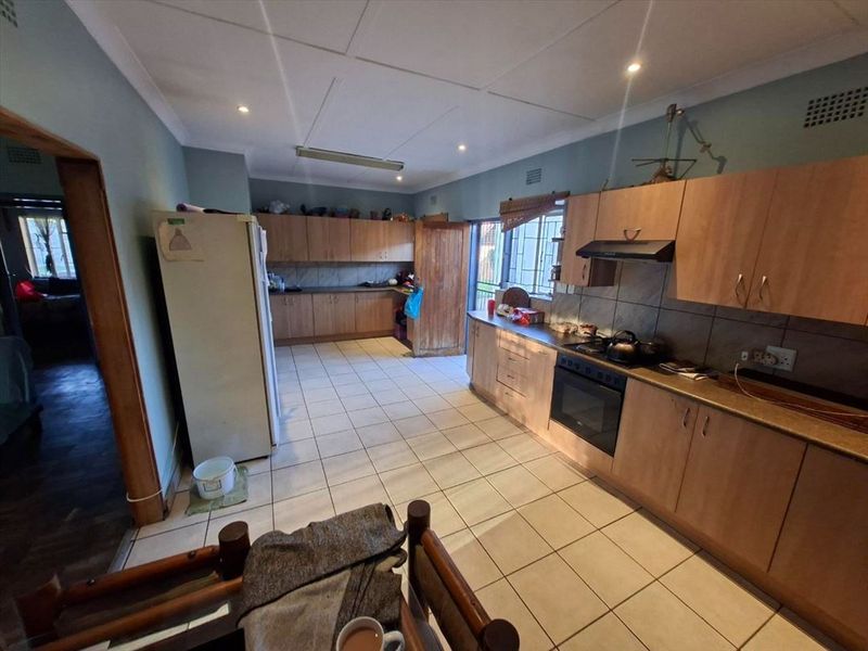 Spacious kitchen featuring extensive built-in cabinetry, tiled flooring, and integrated cooking appliances, offering a functional layout with ample storage space.