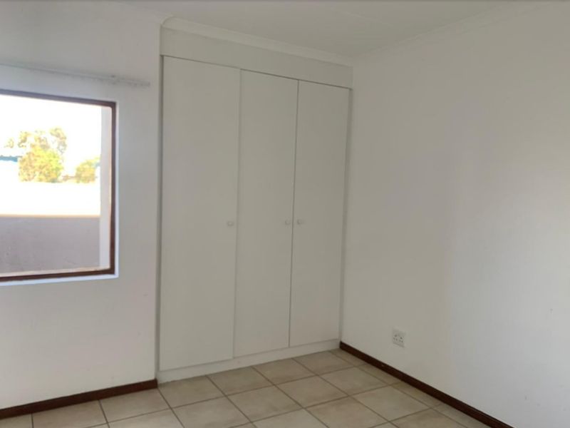 A clean, empty bedroom featuring neutral tiled flooring and a built-in white wardrobe, offering a blank canvas for personalization.