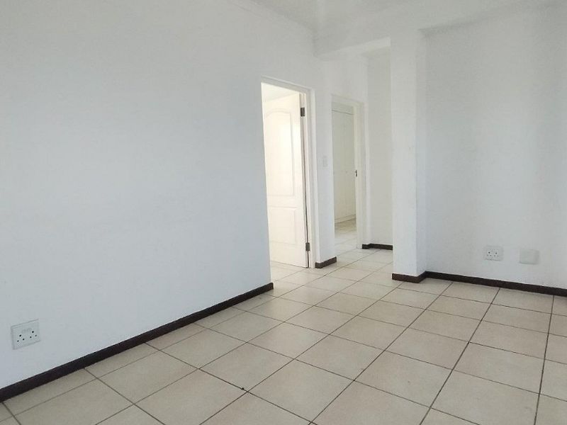 An empty, neutral living area featuring ceramic floor tiles and clean white walls, providing a blank canvas for interior design.