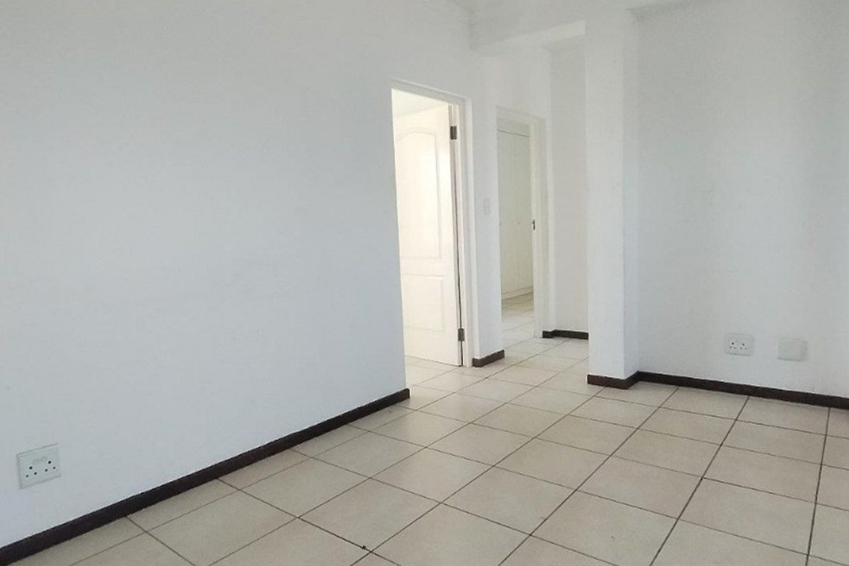 An empty, neutral living area featuring ceramic floor tiles and clean white walls, providing a blank canvas for interior design.