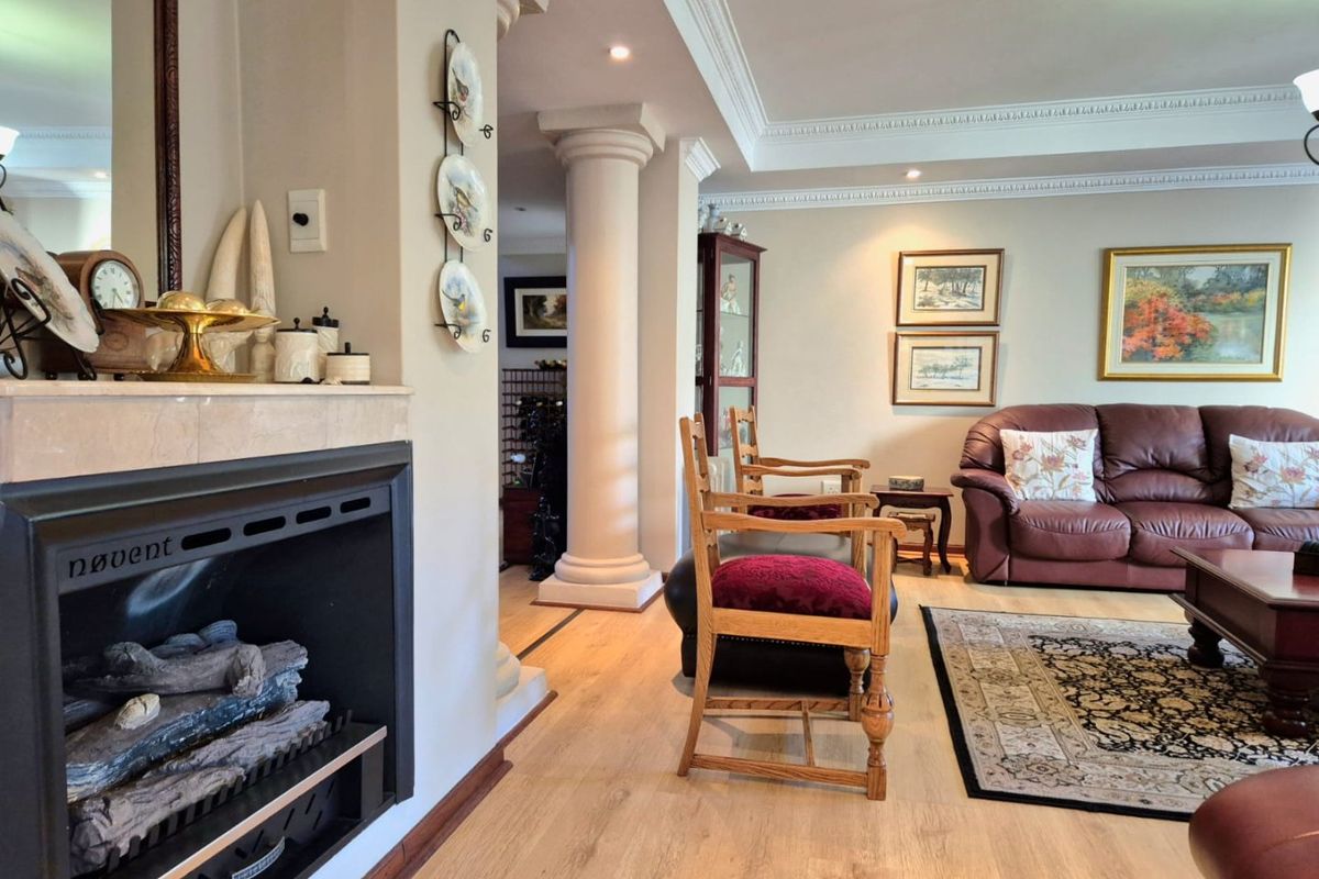 Spacious living room featuring a built-in fireplace, decorative columns, crown molding, and light-toned laminate flooring, creating a warm and inviting atmosphere.