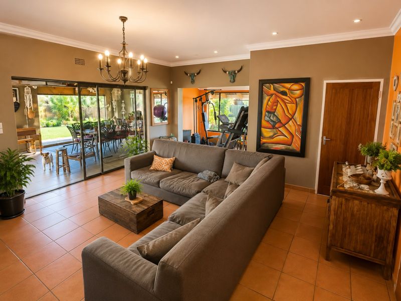 Spacious living room featuring tiled flooring, coved cornicing, and large sliding glass doors that provide seamless access to the outdoor patio area.
