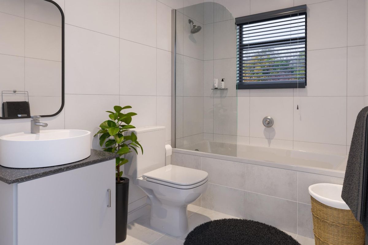 Modern bathroom featuring a white vanity with a vessel sink, a toilet, and a bathtub with a glass shower screen and wall-mounted shower head.