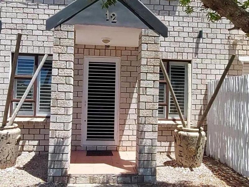 Front entrance of a brick-faced house featuring a covered porch, security gate, and window shutters.