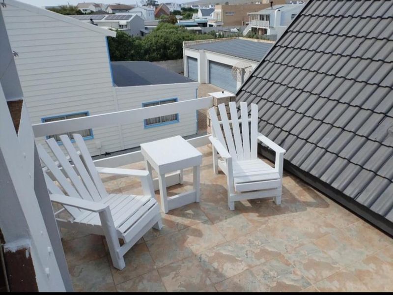 An elevated balcony featuring tiled flooring and a safety railing, offering an open-air space with views of the surrounding neighborhood.