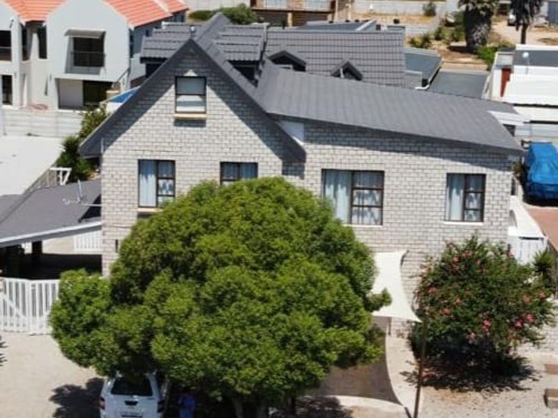 An elevated view of the front elevation of a two-story brick house featuring a tiled roof, driveway, and carport in a residential neighborhood.