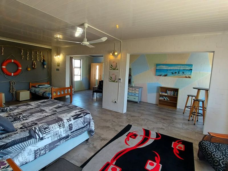 Spacious open-plan bedroom and living area featuring tiled flooring, painted brick walls, and a ceiling fan.