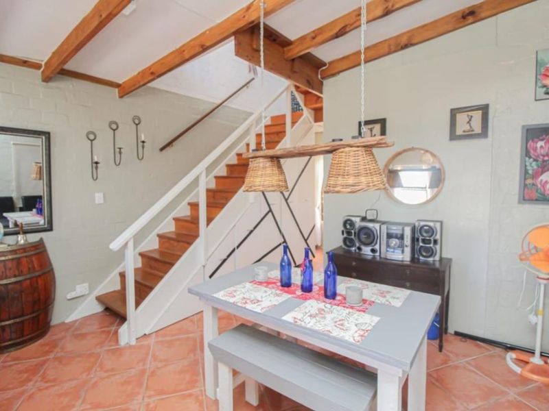 Dining area featuring exposed timber ceiling beams, terracotta floor tiles, and a timber staircase leading to the upper level.