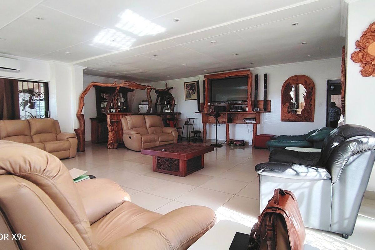 Spacious living area featuring tiled flooring, recessed ceiling lighting, and a wall-mounted air conditioning unit.