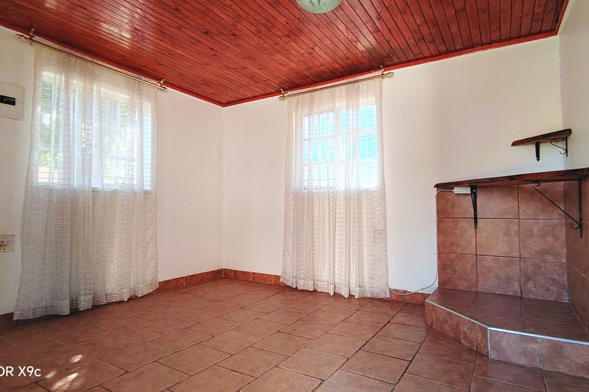 An empty living room featuring a timber ceiling, tiled flooring, and a built-in tiled fireplace hearth.