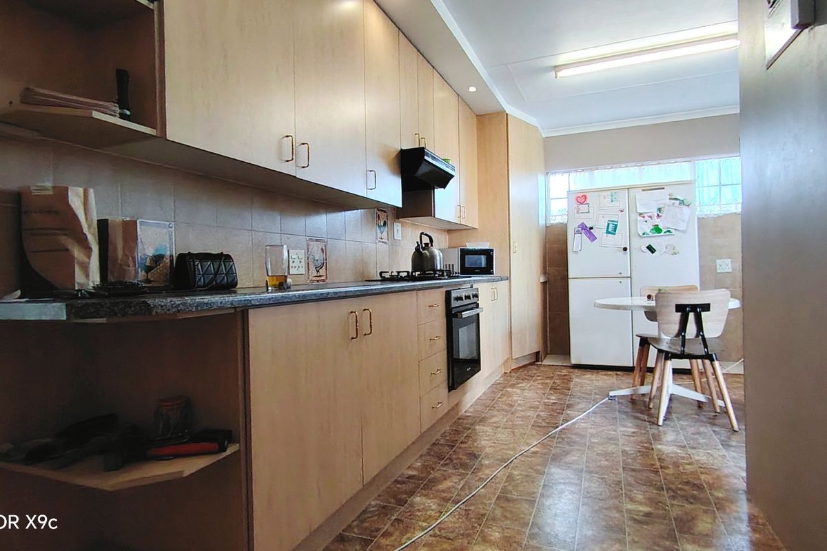 Functional kitchen featuring light wood-tone cabinetry, tiled backsplash, built-in oven, and hob, with an adjacent casual dining area.