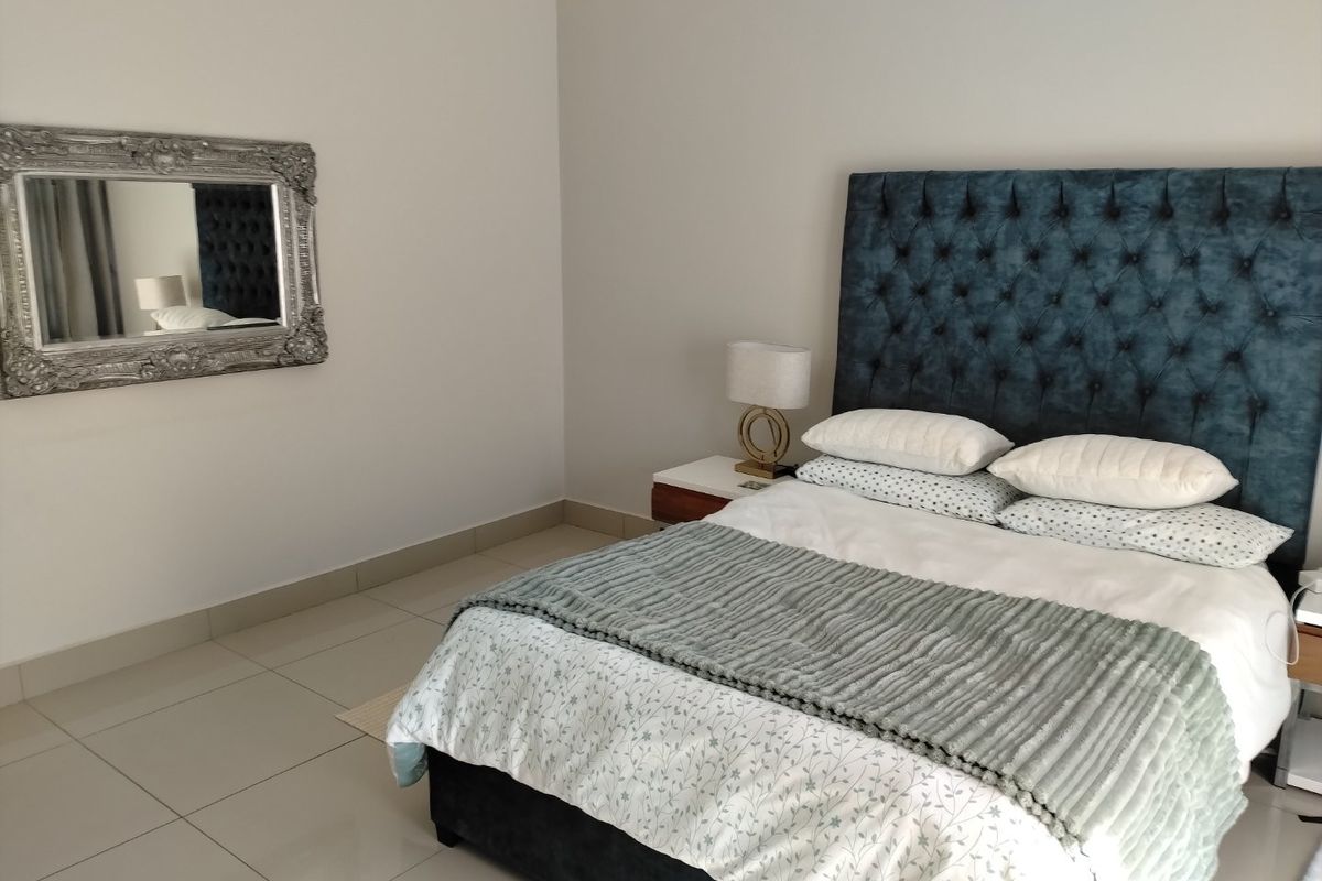 A well-maintained bedroom featuring neutral wall tones and clean tiled flooring, providing a bright and comfortable living space.