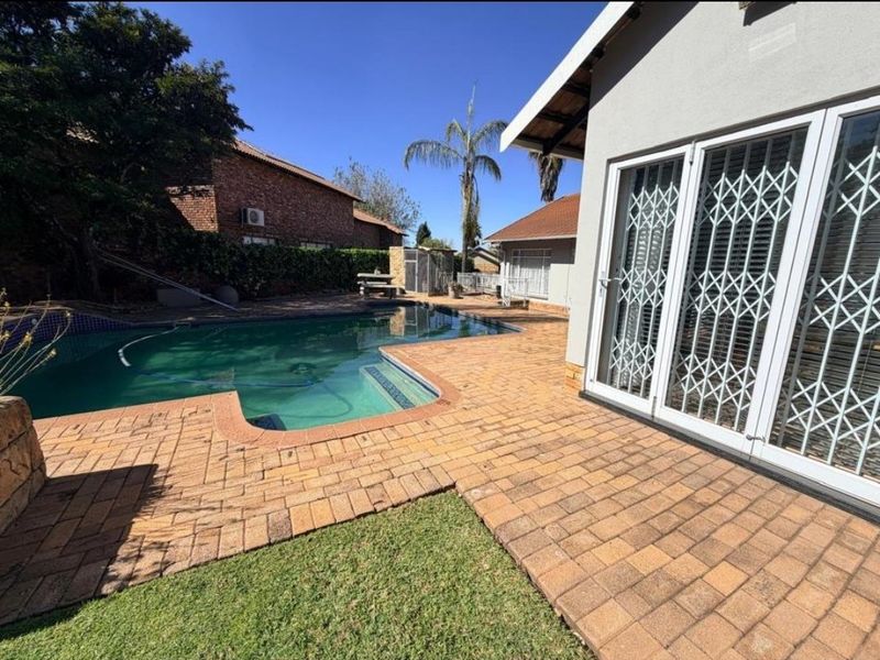 Outdoor pool area featuring a paved patio, swimming pool, and direct access to the home through secure sliding doors.