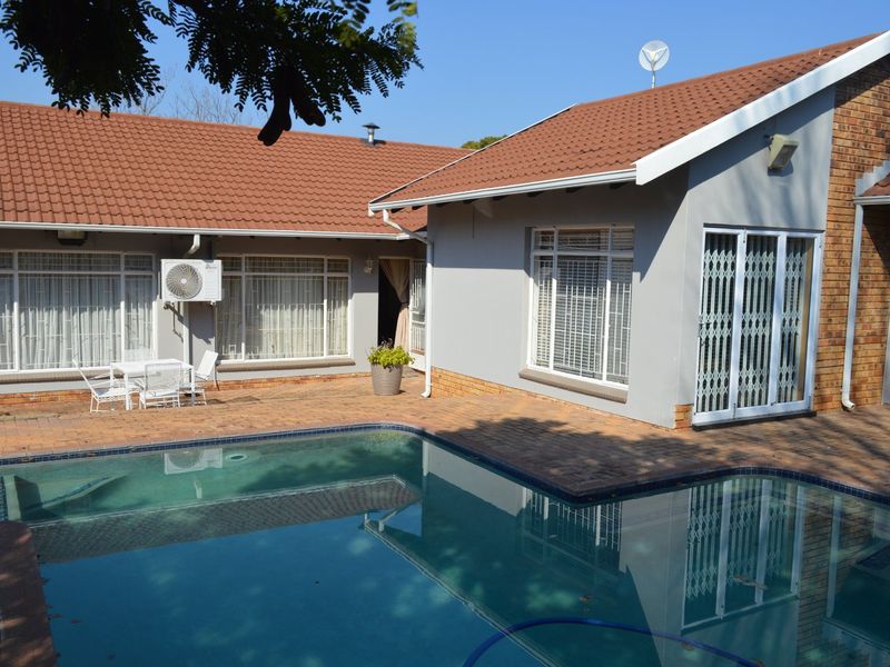 Rear exterior view featuring a swimming pool, brick paved patio area, and access to the main house with security gates and tiled roofing.