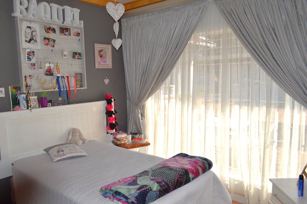 A bedroom featuring a large sliding glass door with curtains, providing natural light and access to the exterior.