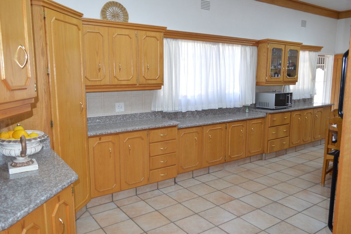 A functional kitchen featuring traditional oak-style cabinetry, granite countertops, and ceramic tile flooring, offering ample storage and workspace.