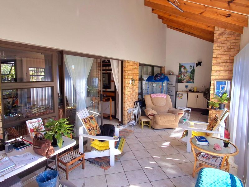 A spacious covered patio featuring exposed timber rafters, face brick walls, and tiled flooring, providing a versatile outdoor living area with sliding door access.