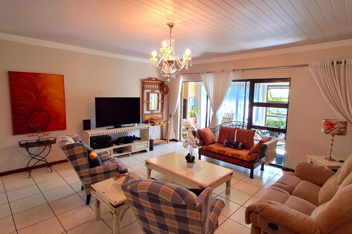 Spacious living room featuring tiled flooring, a classic tongue and groove ceiling, and large sliding glass doors providing access to the patio area.