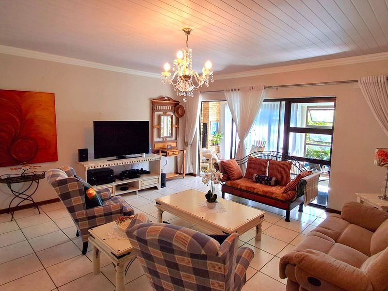 Spacious living room featuring tiled flooring, a classic tongue and groove ceiling, and large sliding glass doors providing access to the patio area.