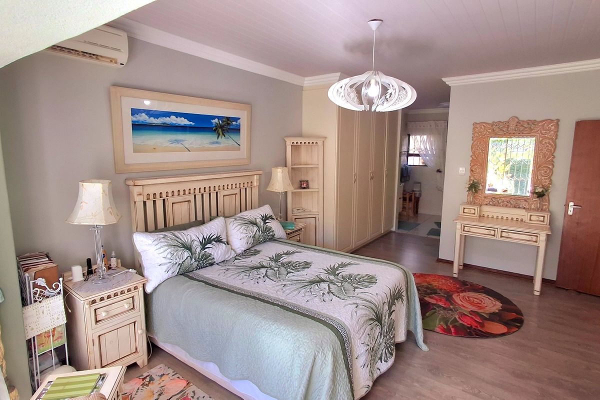 A spacious bedroom featuring built-in cupboards, air conditioning, and timber-look flooring, offering a comfortable and functional living space.