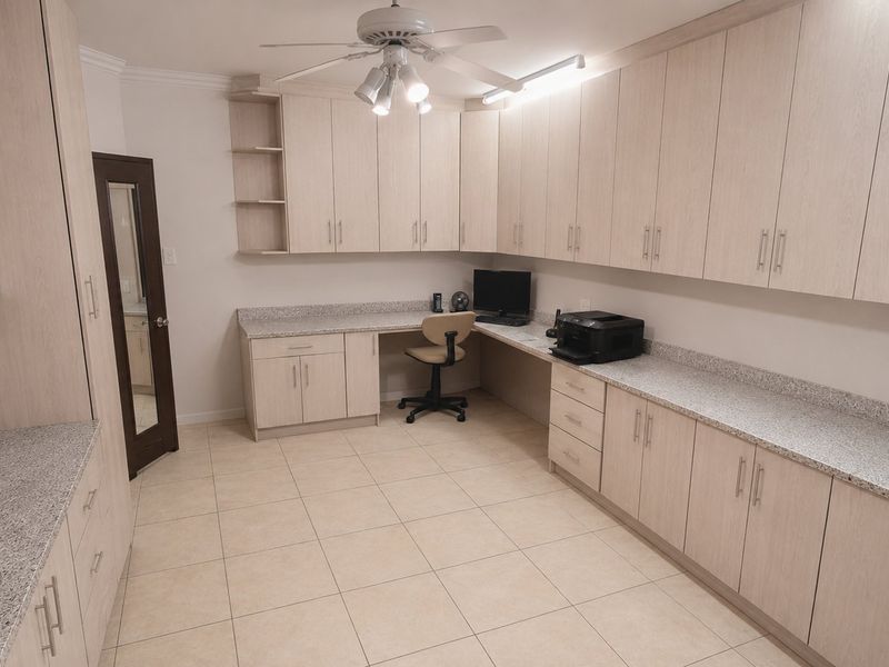 A well-appointed home office featuring extensive built-in cabinetry, granite countertops, and durable ceramic tile flooring, providing ample storage and workspace.