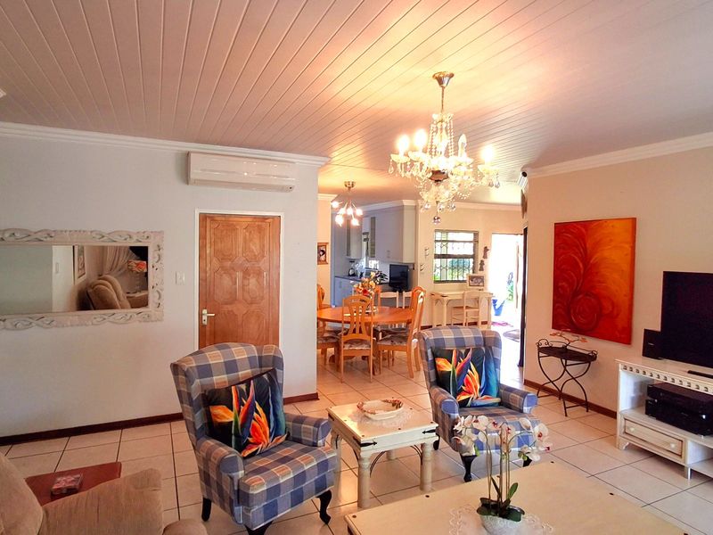 Open plan living and dining area featuring tiled flooring, timber panelled ceilings, and an integrated air conditioning unit.