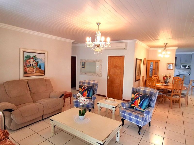 Spacious open-plan living and dining area featuring tiled floors, tongue and groove ceilings, and an integrated kitchen with built-in cabinetry.