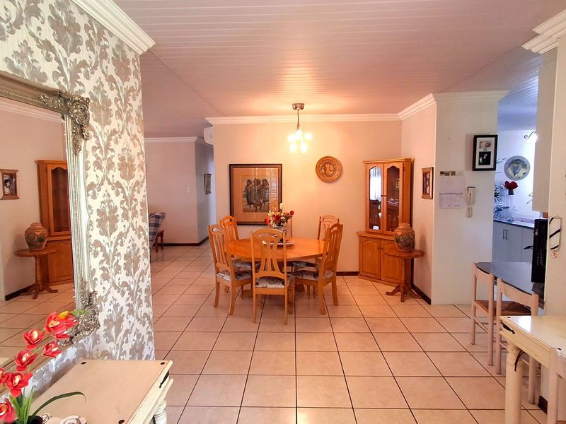 Open plan dining area featuring ceramic floor tiles, coved cornicing, and a tongue and groove ceiling, with a view through to the kitchen area.